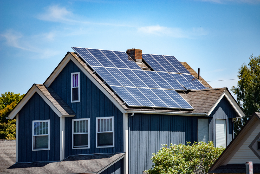 A nice home with blue siding and several solar panels on the roof.